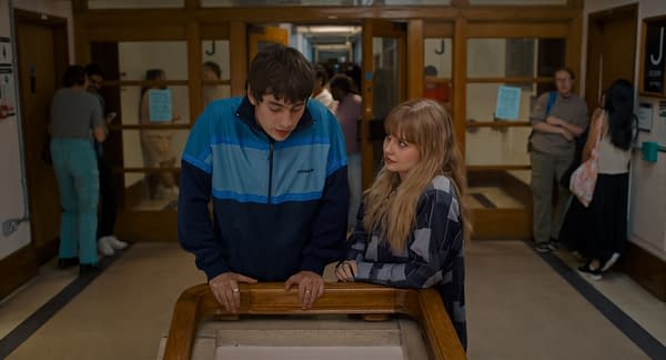 Spike Fearn and Angourie Rice stand close together in a school hallway in Finding Emily, with him leaning on a railing as she looks up at him.