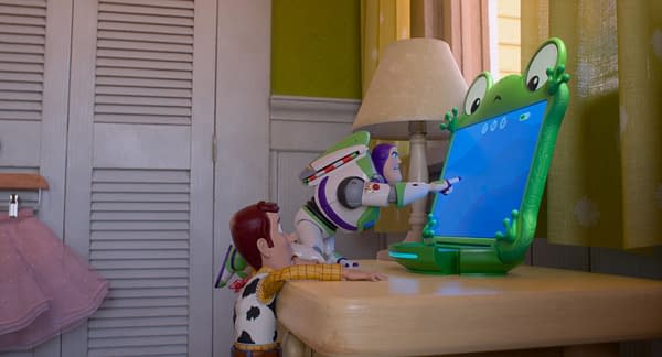 Woody and Buzz Lightyear watch Lilypad, a green frog-shaped screen, in a Toy Story 5 scene.