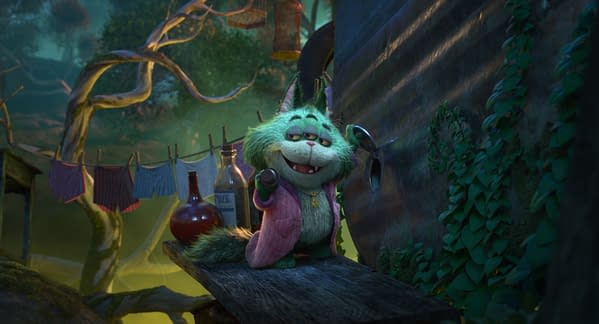 Beef Roger Crummchuk, a fuzzy green animated cat from Disney's Hexed, stands on a branch in a magical forest. He wears a pink cardigan and grins beside hanging laundry and potion bottles.