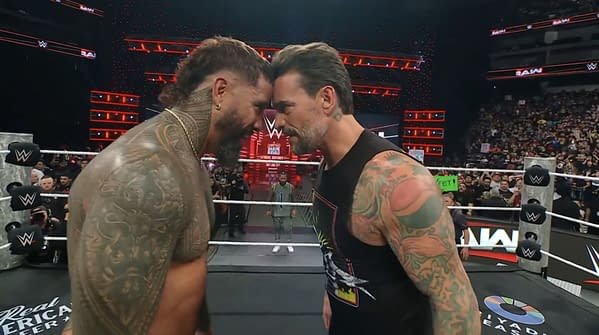 CM Punk and Jey Uso are playfully pressing their foreheads together in a humorous moment on WWE Raw, with a wrestling ring and an enthusiastic crowd in the background.