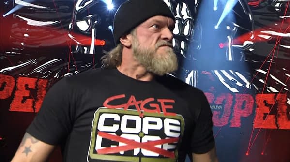 Wrestler Adam Copeland returns from injury at AEW Revolution, wearing a black shirt with bold red and green lettering and a beanie, showcasing an intense expression against a background of dramatic lighting and graphics.