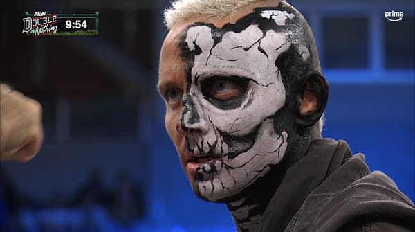 Darby Allin, with his signature black-and-white face paint, looks stunned during AEW Double or Nothing as a fist enters the frame at left. The broadcast timer and AEW Double or Nothing logo appear in the corner.