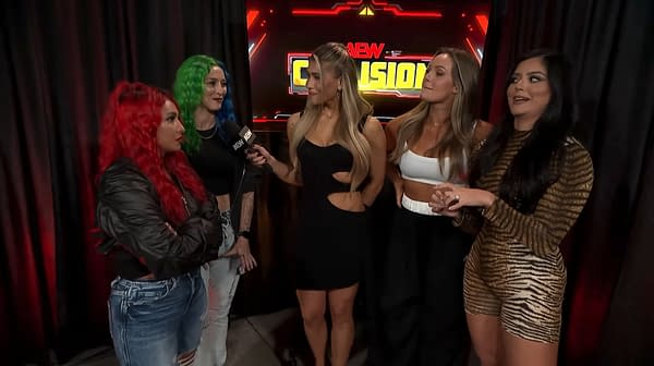 Nixon Newell and Miranda Alize, wearing vibrant hair and stylish outfits, interrupt a backstage interview with Anna Jay and Tay Melo during AEW Collision. The setting features a dark backdrop with colorful event branding, highlighting the drama of the moment.