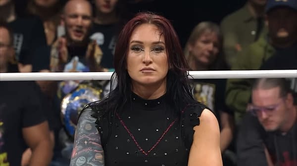 Kris Statlander, a former AEW champion, stands with an unimpressed expression during a promo segment. The wrestling ring is in the foreground with a crowd visible in the background.