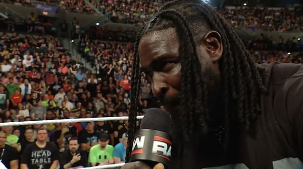 Oba Femi speaks into a WWE Raw microphone inside the ring, with a packed arena crowd behind him. He appears to be issuing a SummerSlam challenge.