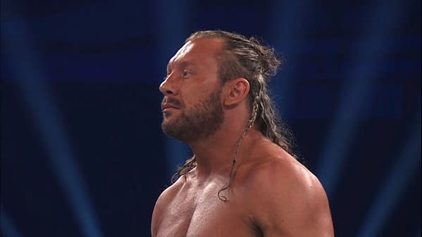 Kenny Omega stands in the ring under blue arena lights at AEW All In London, shown in profile during a title match.