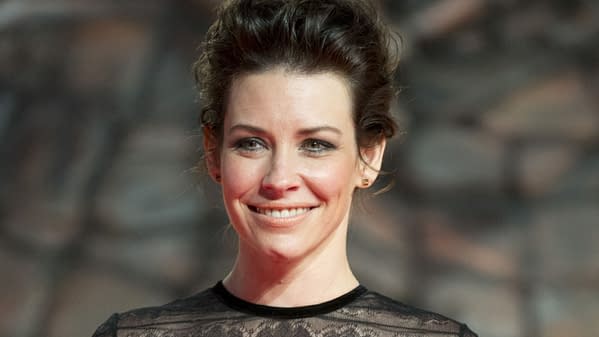 Evangeline Lilly smiles at the premiere of 'The Hobbit: The Desolation of Smaug' in Berlin, wearing a black lace dress. The image captures her at the event held on December 9, 2013, highlighting her as a notable celebrity in the movie industry.