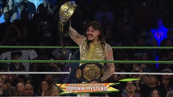 Dominik Mysterio triumphantly holds the AAA Mega Championship belt above his head while wearing a skeletal-patterned outfit, surrounded by enthusiastic fans in a wrestling ring.