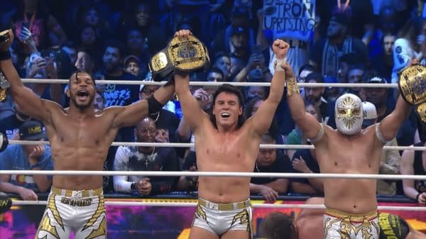 Kevin Knight, Mike Bailey, and Místico celebrating their victory as World Trios Champions at AEW Revolution, holding championship belts high in the air surrounded by a cheering crowd.