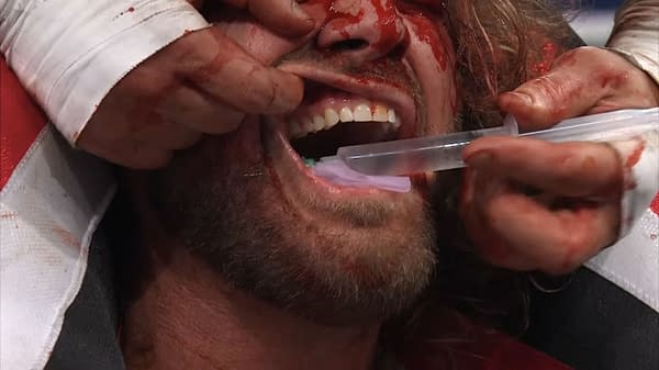 MJF appears to stick a syringe through the cheek of Hangman Adam Page, who is covered in blood, during a Texas Death Match at AEW Revolution. The intense moment captures the brutality of professional wrestling.