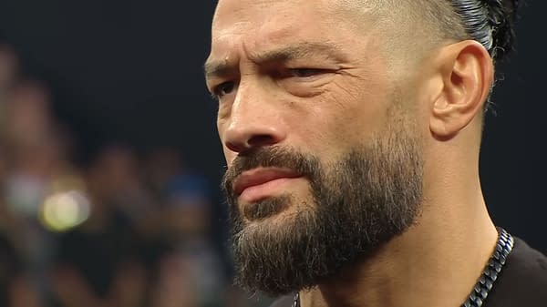 Close-up of Roman Reigns on WWE Raw, looking unimpressed and skeptical. His expression suggests tension in a confrontation with Seth Rollins.