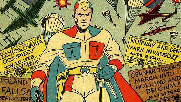 Victory Comics #1 (Hillman Publications, 1941). A superhero, The Conqueror, stands confidently with a star emblem on his chest, holding weapons. Behind him, parachutes drop from planes amidst newspaper headlines about wartime events.