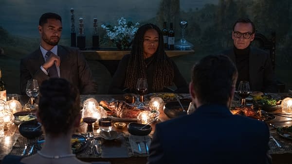 A dimly lit dining table is set with gourmet dishes and wine glasses, featuring a group of elegantly dressed individuals deep in conversation. The image illustrates a tense and stylish atmosphere, perfectly capturing the essence of Soderbergh's latest thriller, "Black Bag."