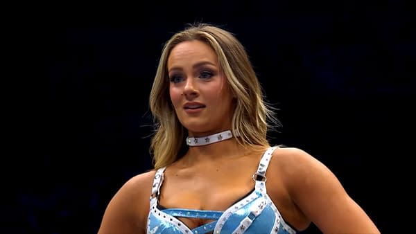 A female wrestler, Anna Jay, stands in the ring wearing a blue and silver wrestling outfit. She has long hair and appears to be waiting for her opponent, Penelope Ford, after her return at AEW Collision.
