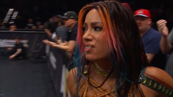 Mercedes Moné shows her disappointment after losing a tag match, with visibly upset expressions. The audience is slightly blurred in the background, depicting the atmosphere of a wrestling event.