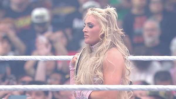 Tiffany Stratton, in a sparkling outfit, stands in the wrestling ring with her championship belt, celebrating her victory against Charlotte Flair at WrestleMania 41, amidst an excited crowd.