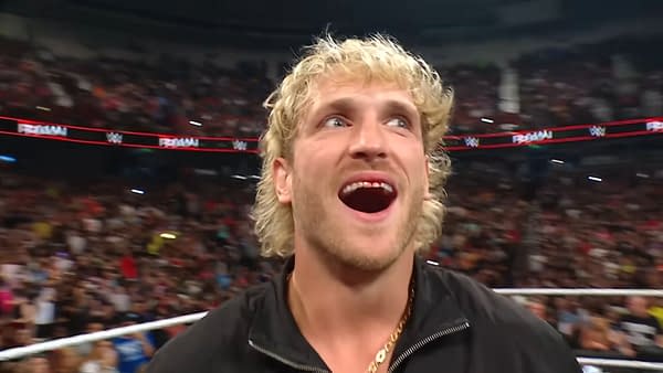 Logan Paul stands with a wide smile, looking energized and confident at the end of a WWE Raw event, with a cheering crowd in the background.