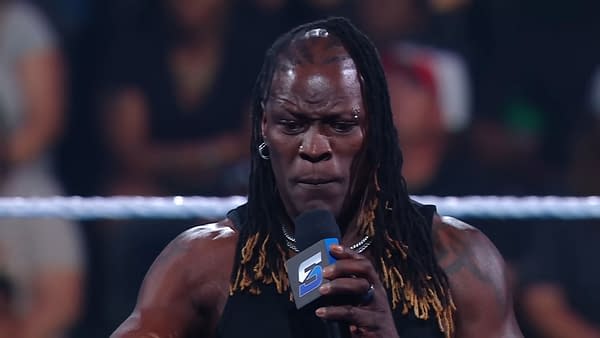 Ron Killings, aka R-Truth, delivers an emotional promo on WWE SmackDown, expressing deep feelings to the audience while holding a microphone and showing intense expression.