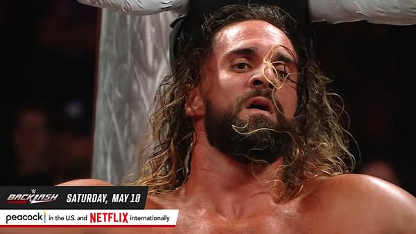 Seth Rollins, a professional wrestler, appears sweaty and intense during a match on WWE Raw, with his long hair partially covering his face and a background of wrestling ring ropes and fans.