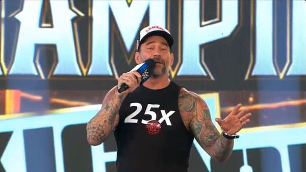 CM Punk, a professional wrestler with tattoos speaks into a microphone while wearing a sleeveless shirt with the number '25x' on it. He appears to be addressing an audience, with a colorful background featuring part of the WWE Night of Champions logo.