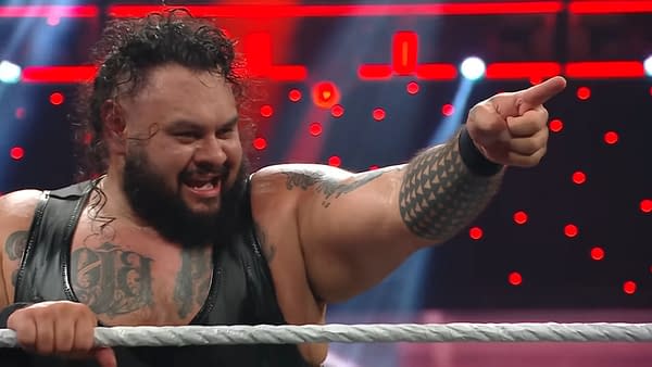 Bronson Reed, a professional wrestler, appears on WWE Raw, passionately pointing while celebrating in the ring. He has long curly hair and visible tattoos on his arms and chest.