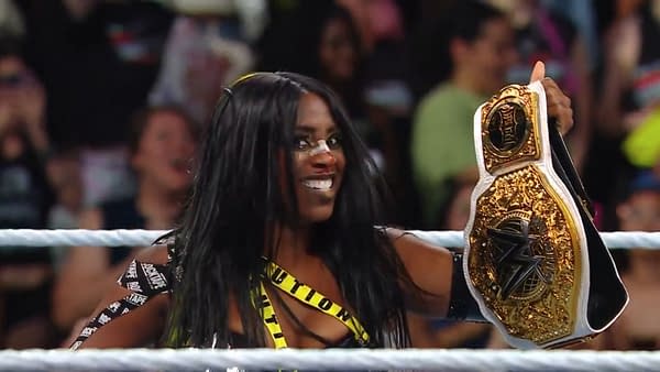 Naomi, with a joyful expression, holds the WWE Women's Championship above her head, showcasing her victory after cashing in at WWE Evolution. She wears a black and yellow outfit with caution tape details, and there is a bandage on her nose.