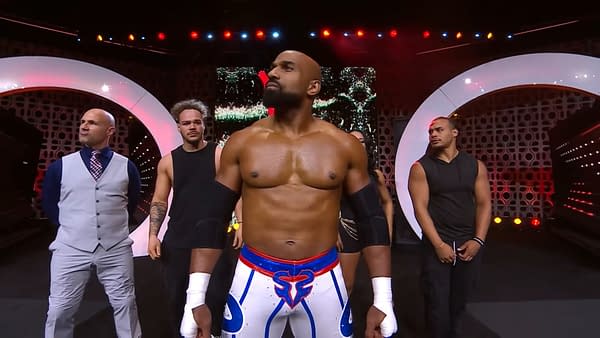 Scorpio Sky is center stage at AEW Collision 100, flanked by Christopher Daniels, Leila Grey, and members of Top Flight. Scorpio is wearing distinctive wrestling gear featuring a blue and white design, with the others dressed in black.