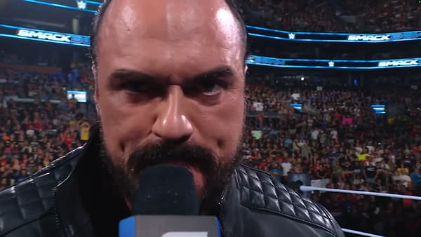 Drew McIntyre delivers a passionate promo on WWE SmackDown, holding a microphone close to his face in front of a large crowd. The excitement of the audience is palpable in the background.