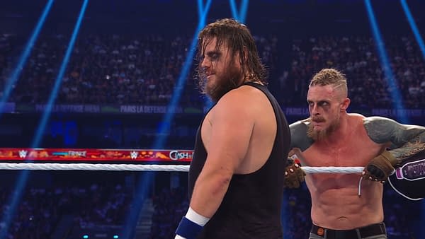 Joe Gacy and Dexter Lumis from The Wyatt Sicks are engaged in a wrestling match during WWE Clash in Paris 2025, with bright lights illuminating the arena.