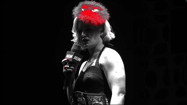 A woman with short blonde hair and red accents is holding a microphone labeled with the AEW logo, wearing a black dress and a shiny championship belt. She stands in a dark setting, giving a promo.