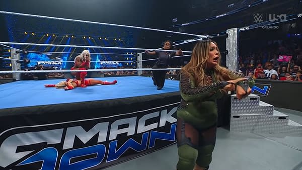 Nia Jax interrupts the WWE SmackDown main event, featuring Tiffany Stratton defending against Jade Cargill, with a dramatic expression. Stratton is down on the mat while Jax gestures intensely at an official.