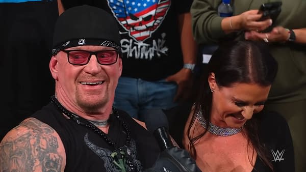 The Undertaker and Stephanie McMahon share a moment at WWE WrestlePalooza, with McMahon announcing her induction into the 2026 Hall of Fame class. The Undertaker is wearing a bandana and sunglasses, showing a playful demeanor.