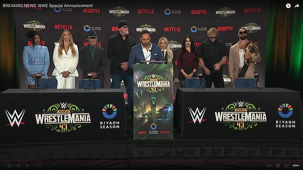 A press conference stage with multiple individuals gathered, featuring a prominent banner announcing WrestleMania 43 in Saudi Arabia, with logos from WWE, Netflix, and Riad Season visible.