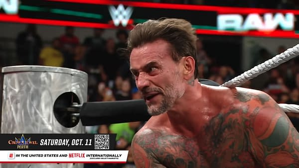 A visibly upset wrestler, with tattoos covering his torso, is yelling while gripping the ropes in a wrestling ring on WWE Raw. The audience can be seen in the background, along with promotional graphics for an upcoming event.