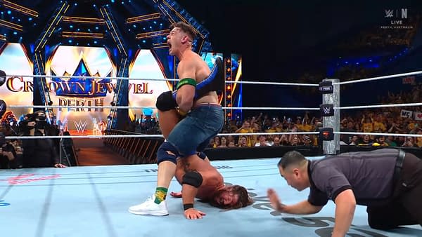 John Cena performs the Walls of Jericho on AJ Styles during a wrestling match at WWE Crown Jewel in Perth. The audience is visible in the background, captivated by the intense action as Cena locks in the finishing move of the legendary Chris Jericho.