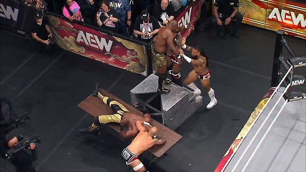 A wrestling match at AEW WrestleDream featuring several competitors in an active scene. One wrestler is seemingly being set up for a move on a table while others are engaged in direct action in the ring.