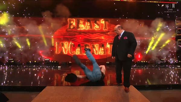 Brock Lesnar is seen slipping and falling on stage during his entrance on WWE Raw, while Paul Heyman looks on with concern amid flashing lights and smoke.
