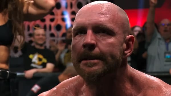 Jon Moxley, a professional wrestler, displays a serious expression as he reacts to a moment in AEW Collision, with fans visible in the background responding to the scene.
