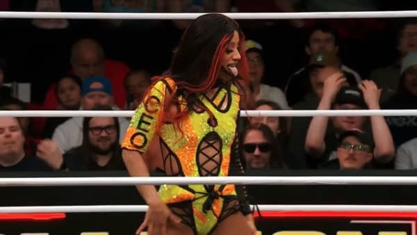 Mercedes Moné performs in the ring at AEW Dynamite and Collision, wearing a vibrant, sequined outfit with orange and yellow hues, showcasing her energetic presence during the main event.