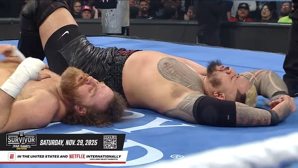 WWE superstars Sami Zayn and Solo Sikoa lie on the wrestling mat, seemingly resting or taking a break during a match. Their expressions reflect exhaustion after a physical encounter.