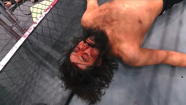 AEW Dynamite: Blood & Guts aftermath sees Wheeler Yuta lies on a wrestling mat, visibly defeated and bloodied, after a brutal Blood and Guts match. The surrounding area shows signs of violence, adding to the scene's intensity.