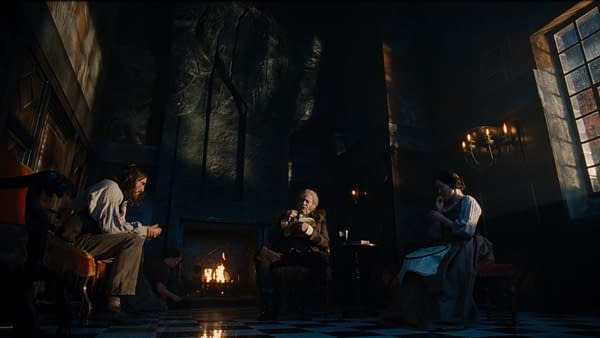 A dramatic scene from "Wuthering Heights," depicting a dimly lit room with a fireplace. Three characters are present: a man seated with flowing hair, an elderly man in a chair, and a woman engaged in sewing, all surrounded by dark, Gothic architectural elements and flickering candlelight.