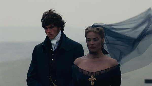 A dramatic scene featuring two characters from "Wuthering Heights." The man, dressed in a dark coat, stands with a serious expression, while the woman, wearing a black off-the-shoulder gown and a veil, appears contemplative, with wind blowing through her hair and veil.