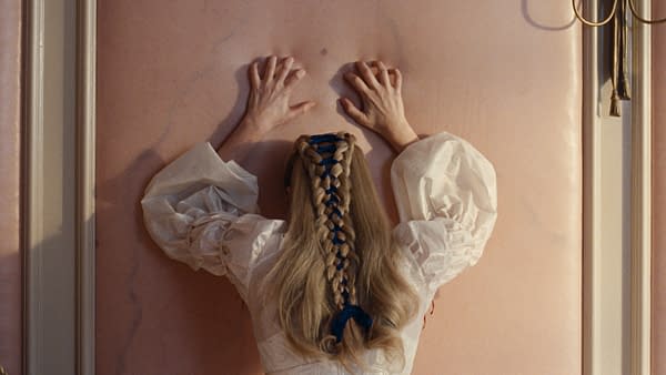 A cinematic scene featuring a woman with long blonde hair styled in a braid, wearing a white dress with puffy sleeves, pressing her hands against a soft pink wall. The image conveys a sense of tension and emotional struggle, reflecting themes from "Wuthering Heights."