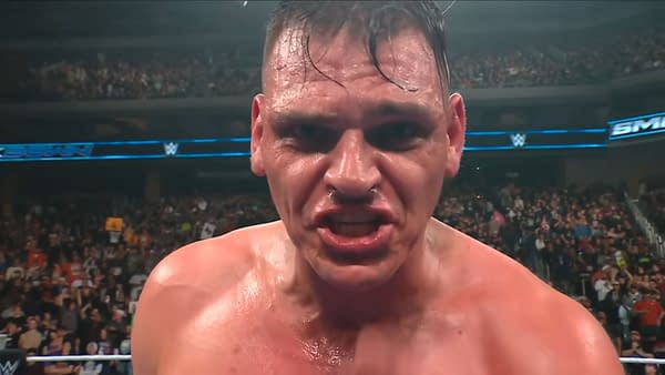 A close-up of Gunther, a wrestler in WWE, appears intense and focused, with sweat on his face and a determined expression. The audience can be seen in the background, creating an energetic atmosphere.