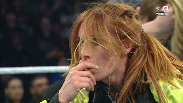 Becky Lynch shows visible frustration during her match with AJ Lee at WWE Elimination Chamber, her hand covering her mouth in a moment of contemplation.