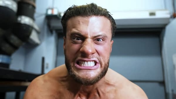 A man with short hair and a fierce expression, showing his teeth, appears agitated as he addresses the camera. He is shirtless with visible muscle definition.