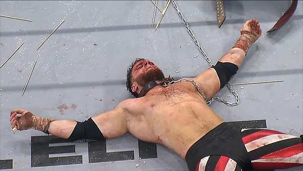 A bloodied wrestler lies on a wrestling mat, chained and surrounded by sharp objects after a violent Texas Death Match. His body is bruised, showcasing the severe physical toll of the match.