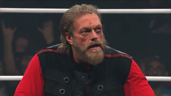 A battered Adam Copeland, with visible bruises and a serious expression, sits wearing a black vest over a red shirt, reflecting the aftermath of a recent match at AEW Collision.