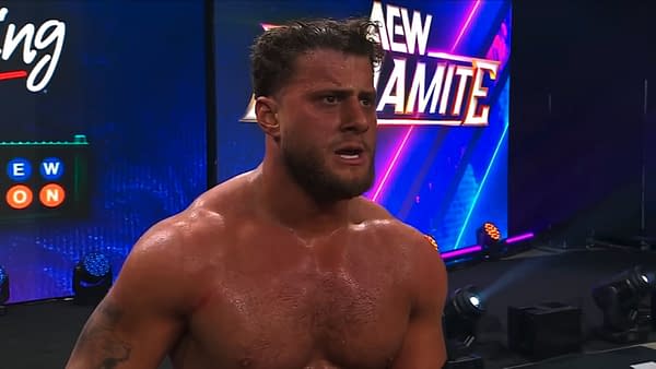 MJF stands shirtless on the AEW Dynamite stage, looking exhausted and frustrated after a match. The AEW logo glows behind him in bright blue and purple lights.